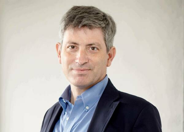 White man with gray hair and brown eyes, wearing a navy sport coat and blue shirt, looking into the camera